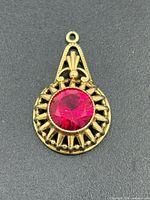 Front view of gold pendant showing ruby and openwork design