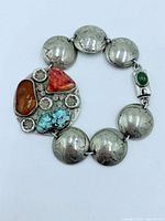 Front view of bracelet showing coin links, gemstone centerpiece, and green cabochon clasp