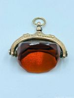 Front view of gold spinner fob showing amber stone and suspension ring