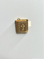 Front view of gold Bible charm showing cross and engraved border