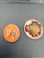 Two oval boulder opal cabochons on black background