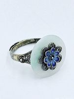side view of silver adjustable ring showing jade disc and enamel flower