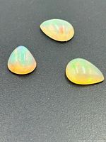 Three Ethiopian opal cabochons on black surface