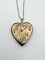 Front view of heart locket showing engraving, floral motifs and central stone