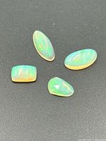 Four opal gemstones on black background showing shapes and play-of-color