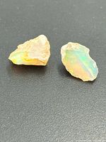 Two rough opal shards on black background showing multicolour play