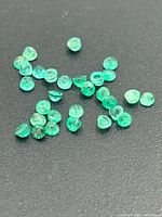 Scattered small emerald gemstones on black surface