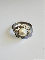 Front view of sterling silver ring with central pearl and decorative openwork setting