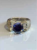 Front view of ring displaying blue center stone and clear baguette stones
