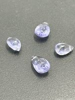 Four pear-shape faceted tanzanites on black surface
