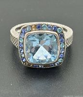 Front view of ring showing cushion-cut blue topaz and halo of blue stones