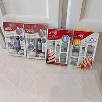 All four Kiss nail product packages standing side by side