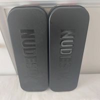 Two black NudeStix metal tins side by side