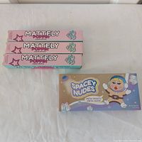 Three stacked Mattely Poppin lipstick boxes beside Spacey Nudes palette box