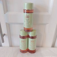 Three stacked sealed Pixi Glow Tonic bottles showing front labels