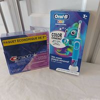Both sealed retail boxes: Oral-B Kids toothbrush and Crest 3D White 3-pack toothpaste