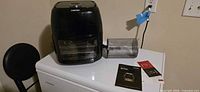 Chefman air fryer oven with accessories on top of freezer, shows main unit, mesh drum, manuals
