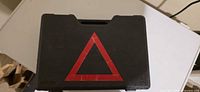 Closed black plastic case with red triangle on lid