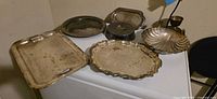 Group of silver-plated trays, cover, shell dish and goblet on surface