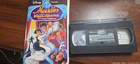 Front view of VHS case alongside tape, showing artwork and label