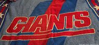 Front of woven throw showing GIANTS wordmark, blue stripe, star border