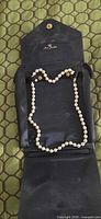 Pearl necklace displayed inside open black folding travel case