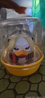 Front view of Harley Quinn vinyl duck inside capsule