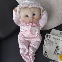 Full view of doll lying on couch showing outfit and bonnet