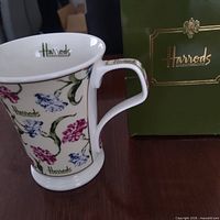 Mug side view showing floral design, Harrods logo and presentation box