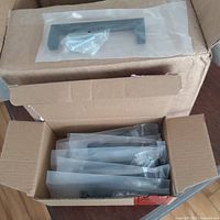 Open box showing multiple individually bagged black cabinet pulls