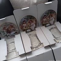 Overview of four boxed porcelain plates with certificates visible