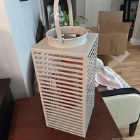 white slatted metal lantern with red candle inside, showing overall design and condition