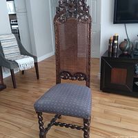 Front view of carved Jacobean-style chair showing cane back, upholstered seat, and barley twist stretcher.