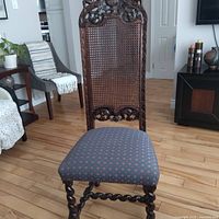 Full view of carved Jacobean style chair showing cane back, upholstered seat, twist legs