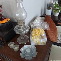 Oil lamp, glass candle holders and packaged candles on table