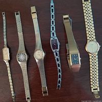 All six wristwatches laid flat showing cases and bracelets