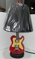 Full view of guitar lamp with shade wrapped in plastic