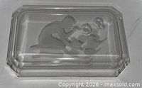 Top view of clear glass tray showing intaglio girl and bird design