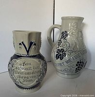Front view of both Wick-Werke stoneware wine pitchers showing size difference, relief decoration and inscriptions
