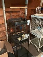 Full view of metal bird cage on stand with adjacent items for scale