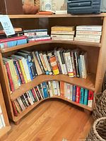 Full view of corner bookcase with books on two shelves and tabletop items