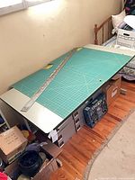 Overhead view of grey laminate work table with cutting mat and straightedge