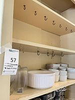 Cabinet shelf holding multiple white ribbed stoneware ramekins and baking dishes