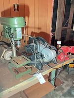 Lot overview showing drill press, two bench grinders, miter saw on workbench