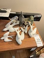 Group shot of seven white birds, blue bird, green bird planter, terracotta warrior on shelf