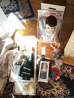 Overview showing boxed baby doll, porcelain dolls, Ty plush moose and jester, and loose doll clothing