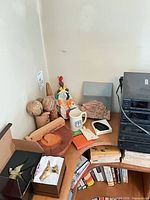 Group view of all small decorative items on shelf including boxes with bird ornaments, gourds, doll, wood pieces, mug and brick model