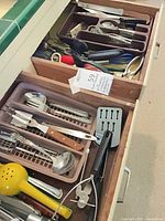 Drawer with two trays showing assorted flatware and utensils
