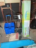 Group shot showing rolling crate, folding hand truck, boxed gazebo, blue chair bag, canvas bag, cane