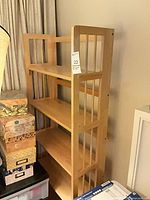 Front angled view of light wood bookcase showing four shelves and slatted sides